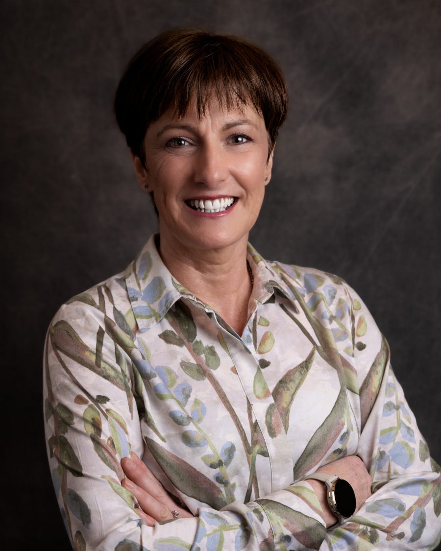 Relaxed business portrait of a woman in a patterned shirt with arms folded