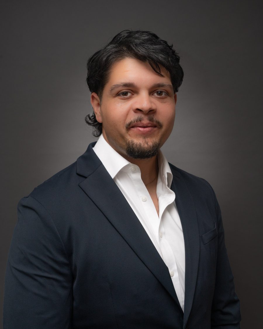 Corporate headshot of a man in a navy blazer and open-neck white shirt