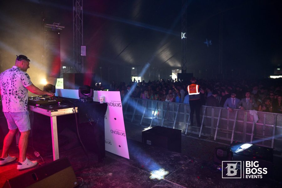 DJ performing under coloured stage lights at an evening event